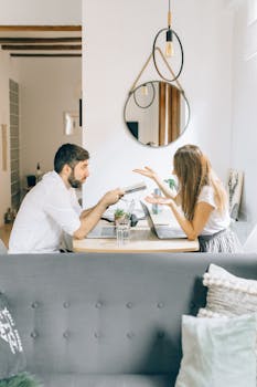 Couple of freelancers having a discussion with laptops at a home workspace, focusing on remote work.