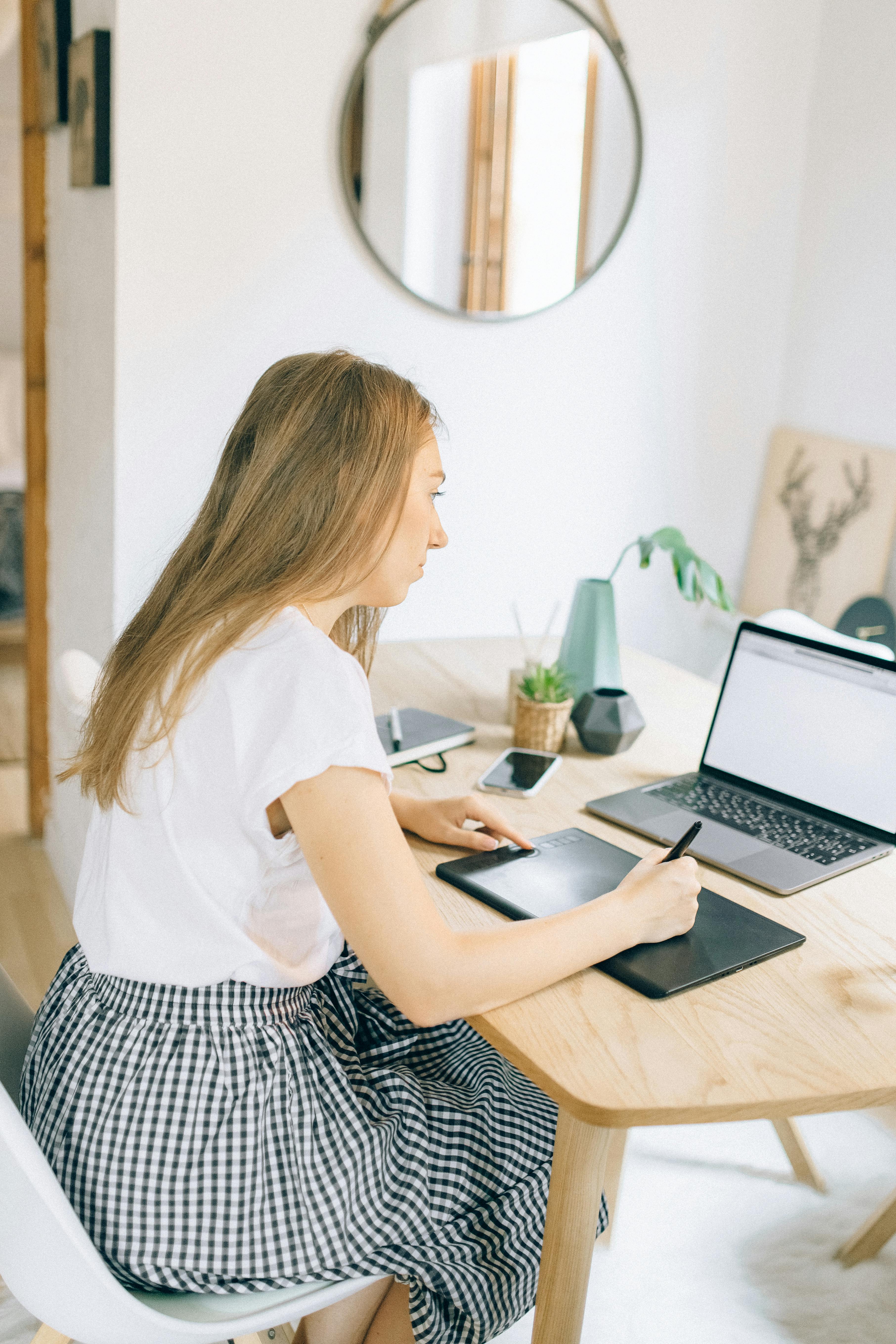 woman in white shirt using macbook air on brown wooden table