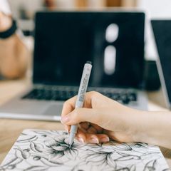 A hand drawing a floral pattern with a pale-barrelled fineliner