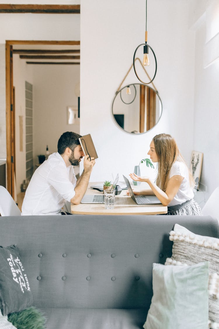 Man And Woman Sitting At Table With Laptops