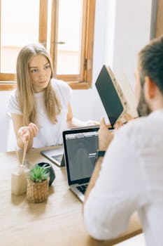A casual meeting between two colleagues in a bright office space.
