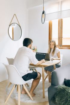 Man and woman collaborating on a laptop in a cozy, minimalist home setup.