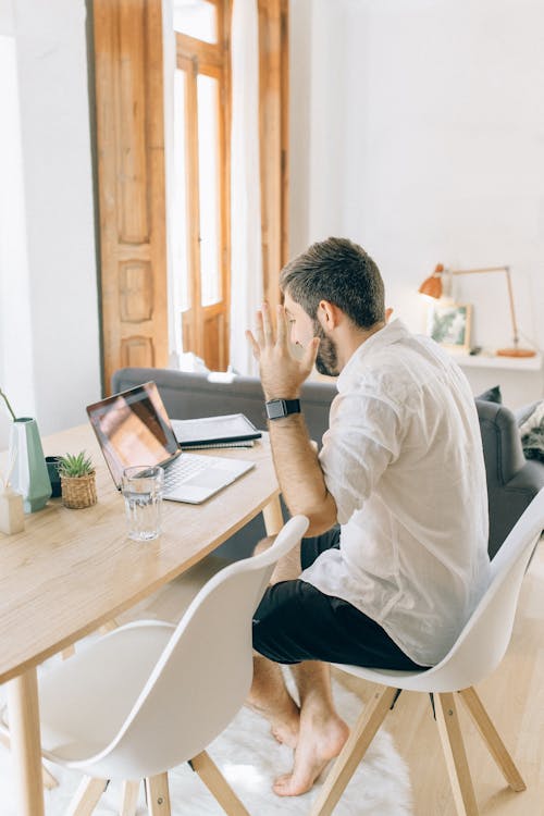 Free Bearded Man Sitting at Wooden Table with Laptop  Stock Photo