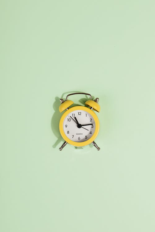 Free Yellow Alarm Clock on Green Pastel Background Stock Photo