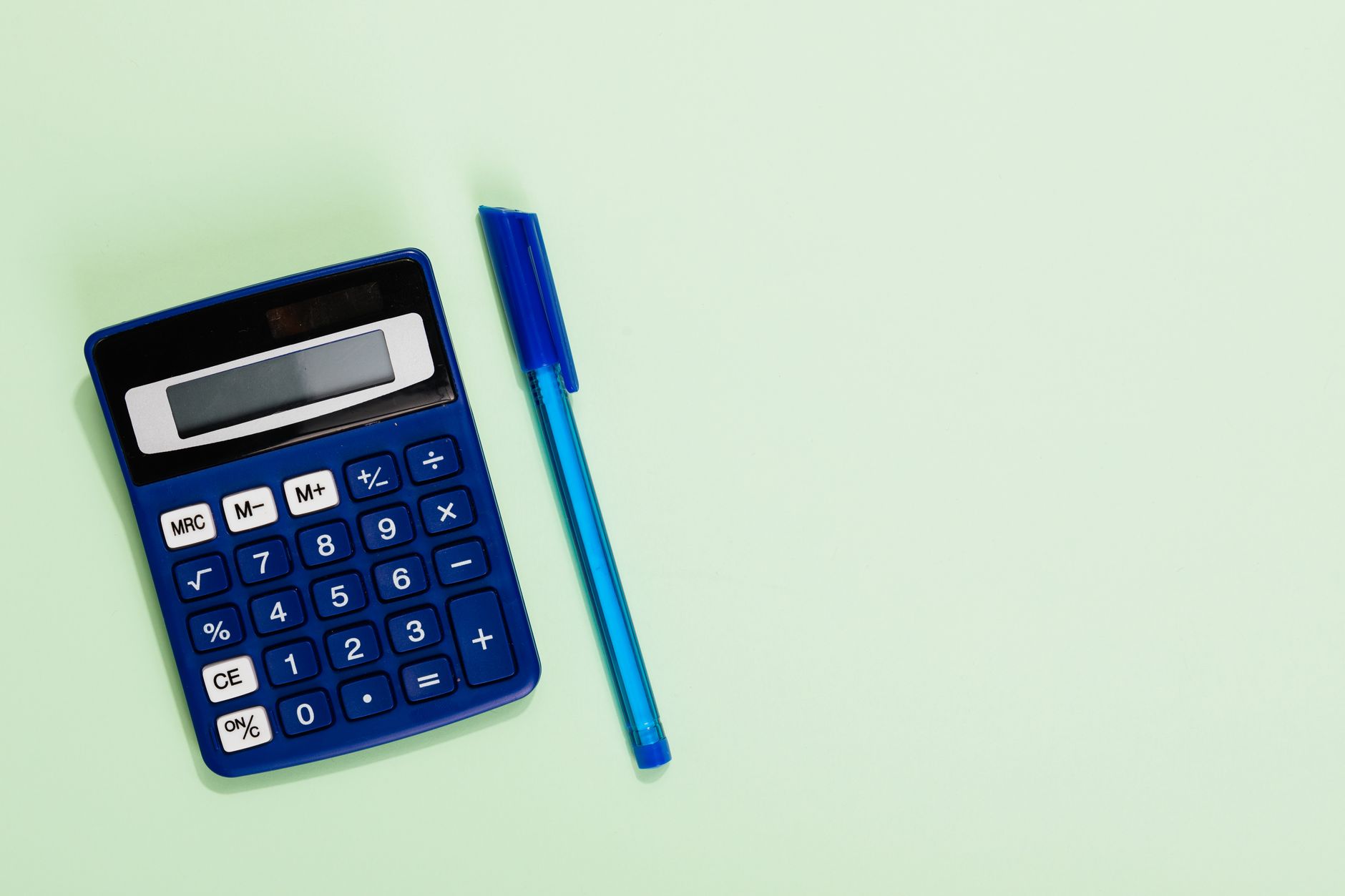 A teal calculator and a white pen on a light background