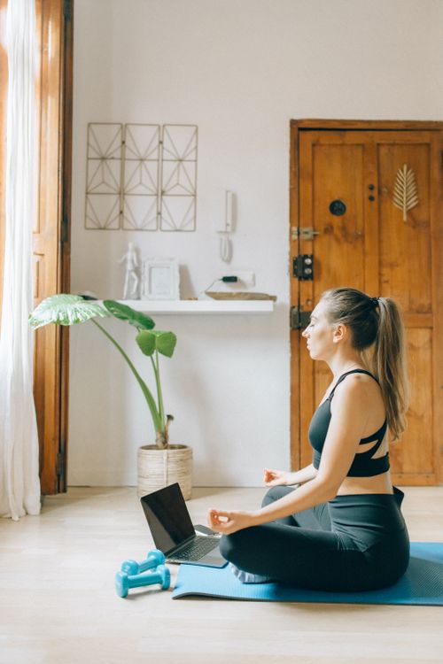 Free Brunette woman practicing yoga at home with a laptop, embracing a healthy lifestyle. Stock Photo