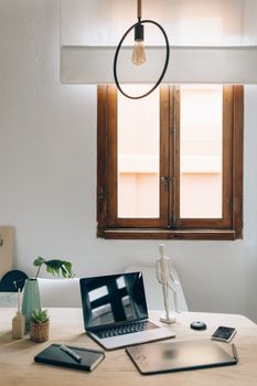 Aesthetic workspace featuring a laptop, decor, and natural light from a wooden window.