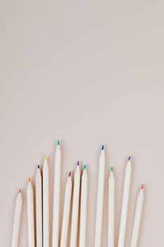 Vertical shot of colorful wooden pencils on a beige background with copyspace.