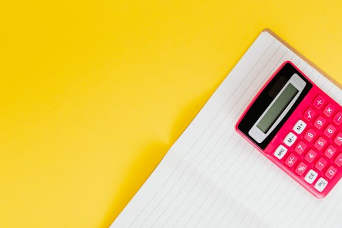Free Red Calculator and Notebook on Yellow Surface Stock Photo