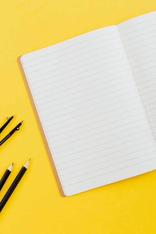 Free  Notebook and Black Pencils on Yellow Surface Stock Photo