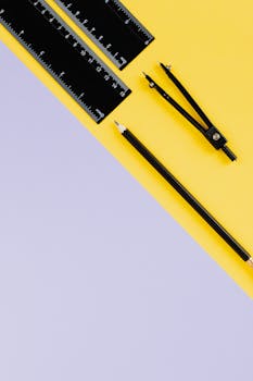 铅笔、尺子和指南针平放在鲜艳的黄紫背景上