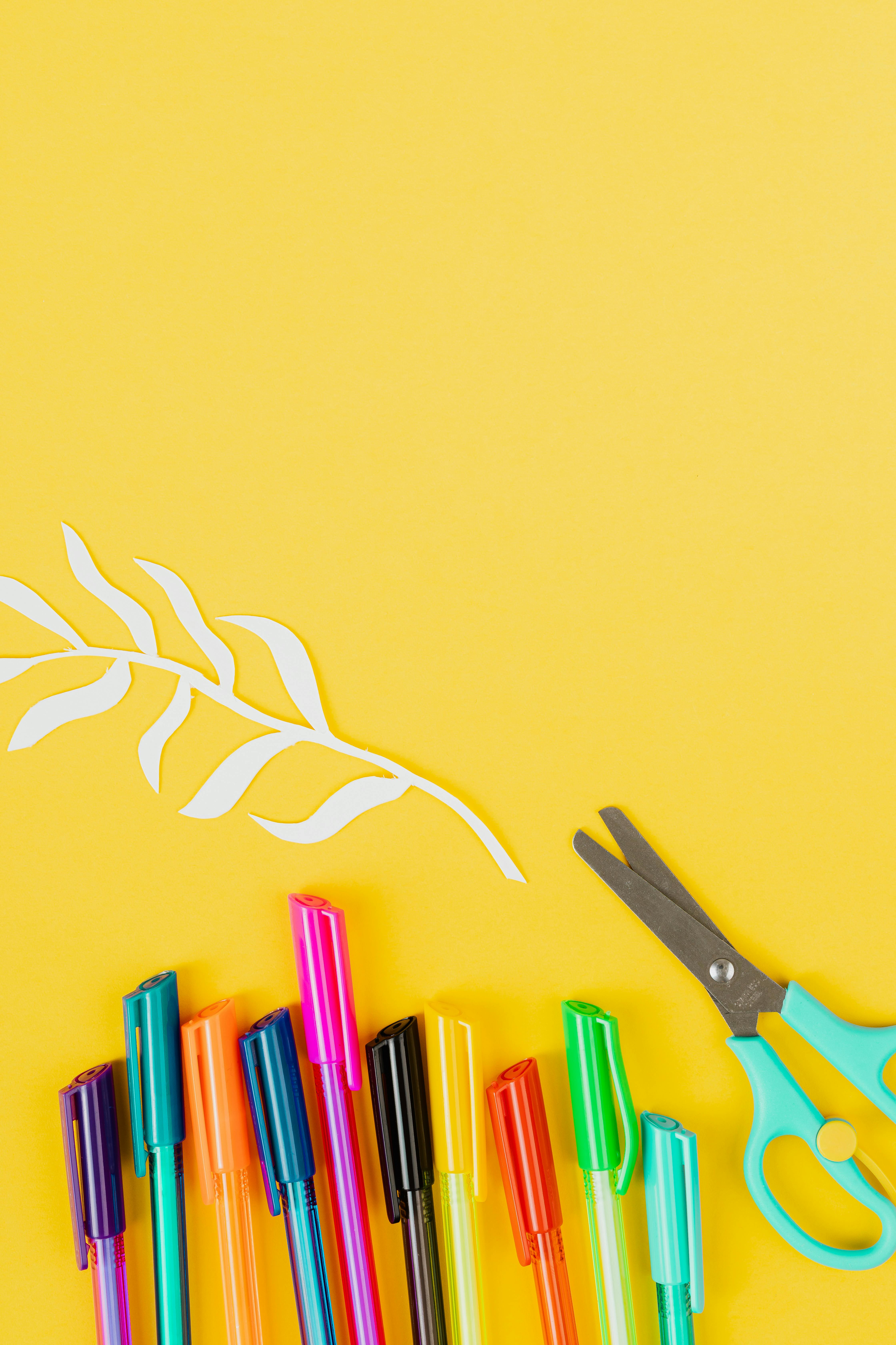剪纸的黄色背景与色彩缤纷的笔和剪刀相搭配