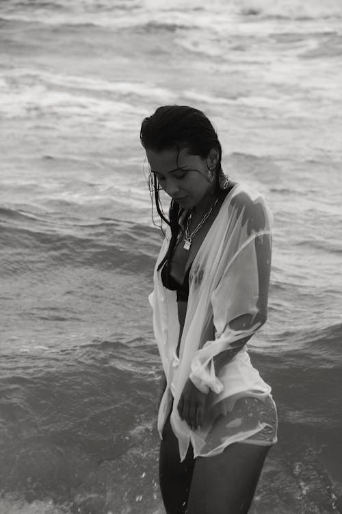 Young woman in wet shirt standing in sea