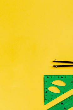 Compass and ruler set on vibrant yellow background with ample copy space.