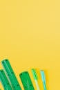 Green Measuring Tools for School and Colored Pens on Yellow Background