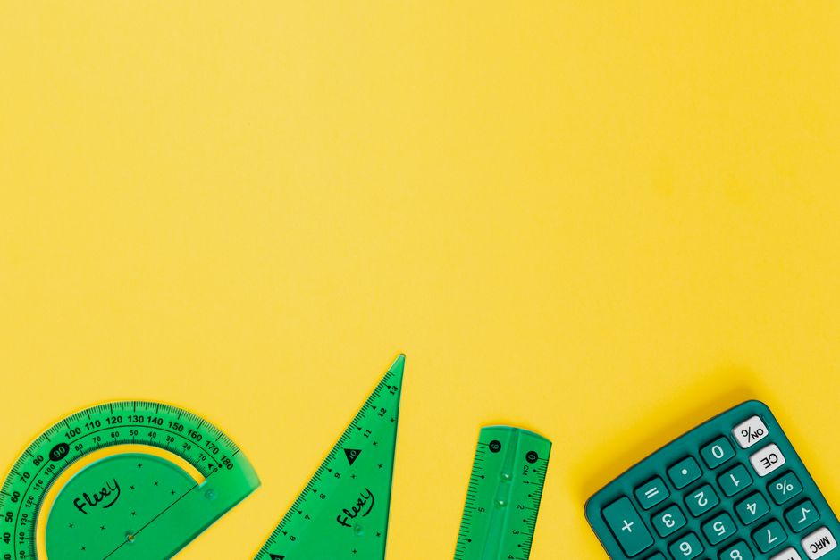Vibrant school accessories including calculator and rulers against yellow backdrop.