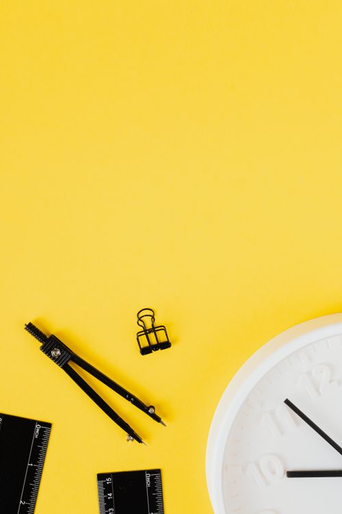 Free Flat lay of school supplies and a clock against a vibrant yellow backdrop, ideal for educational themes. Stock Photo