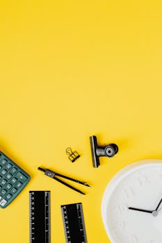 Flat lay of office supplies on a bright yellow background with ample copy space.