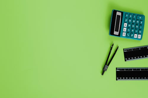 Free Calculator, Rulers and a Compass on a Green Background  Stock Photo