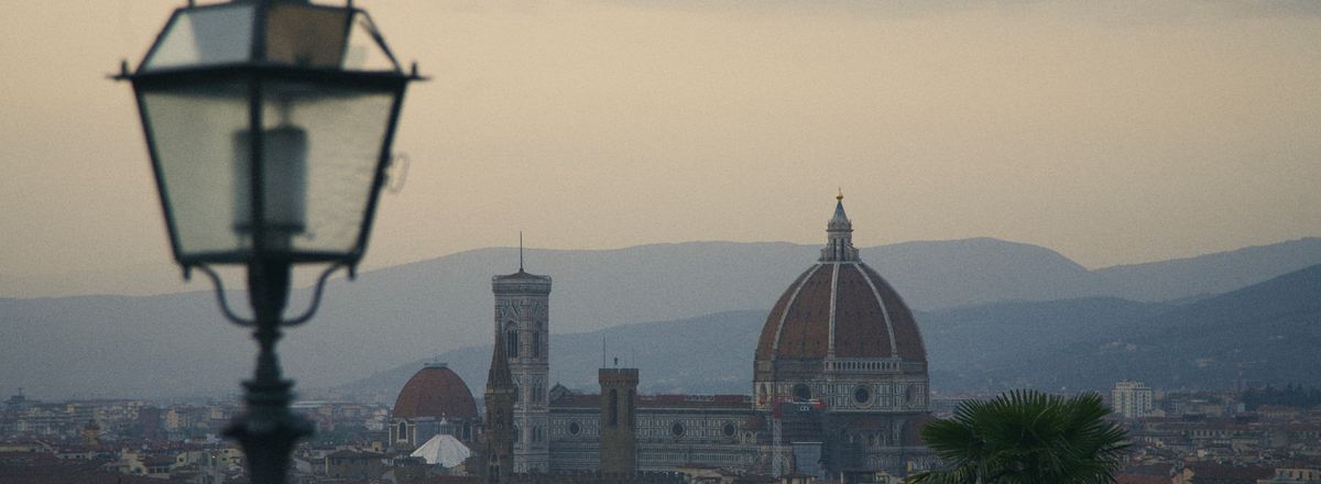 A view of Florence with the iconic Duomo and distant hills under a twilight sky.