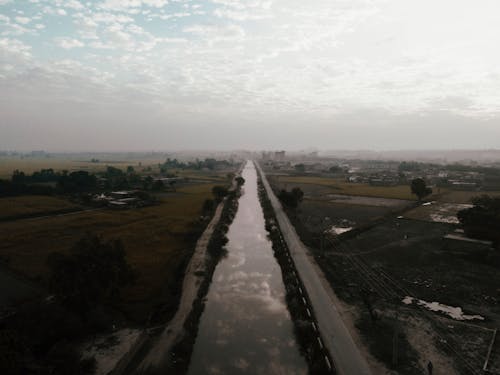 River Between Farmlands Under a Cloudy Sky