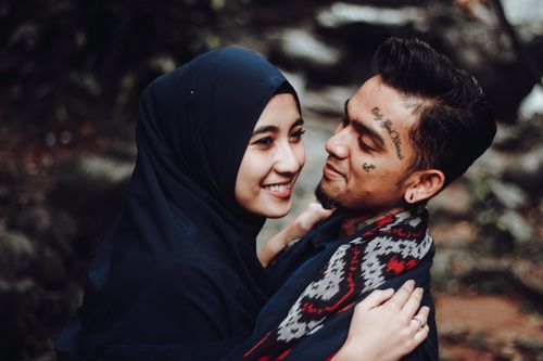 Free A couple shares a joyful moment outdoors, embracing warmly with tattoos and cultural attire. Stock Photo