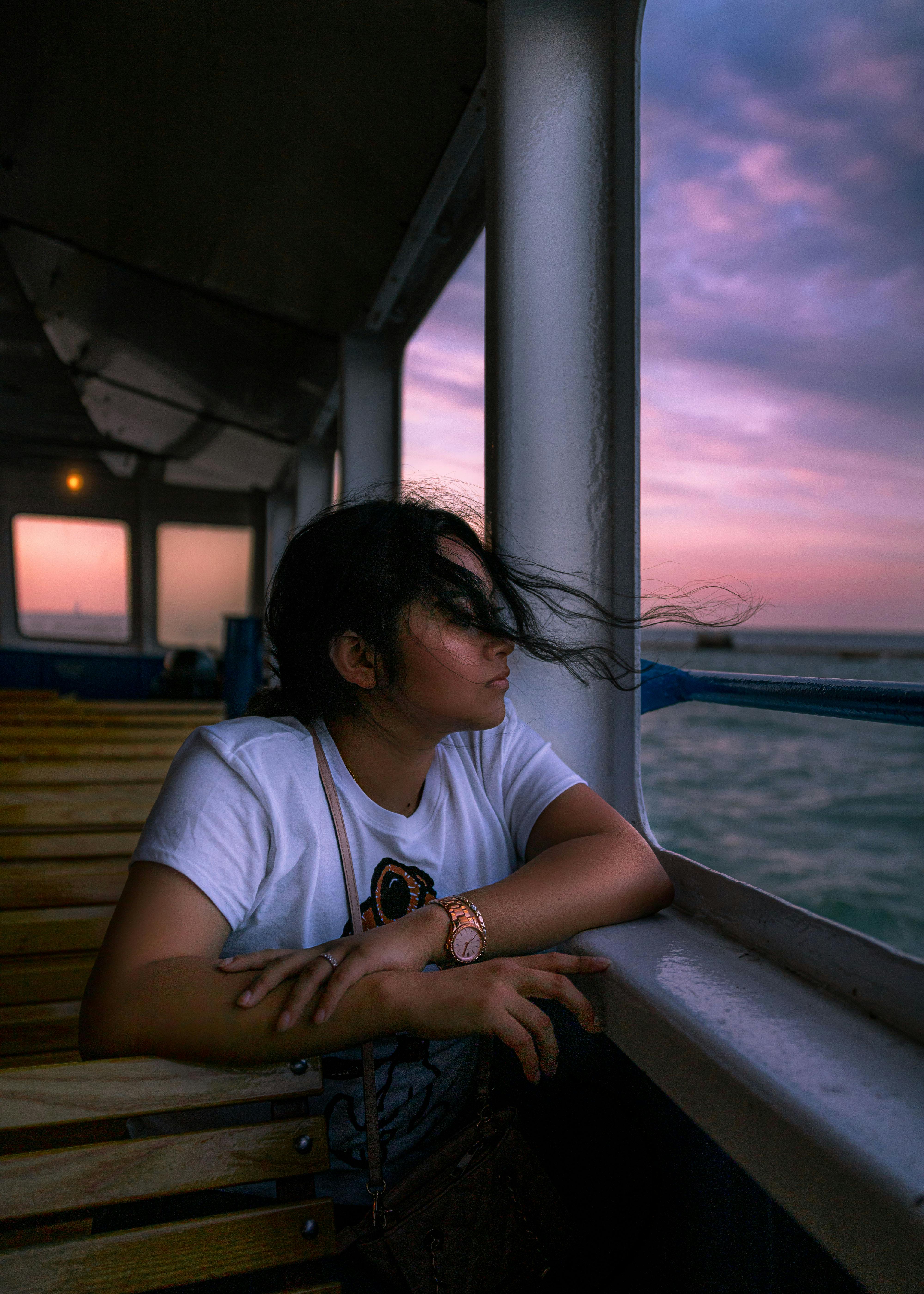 Woman gazes out to sea during a serene ferry ride at sunset, embodying wanderlust.