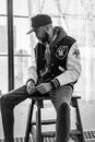A Man in Black and White Jacket Sitting on Wooden Stool