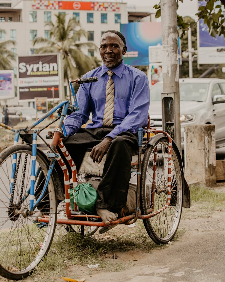 Black Man Sitting On Handmade Tricycle Vehicle