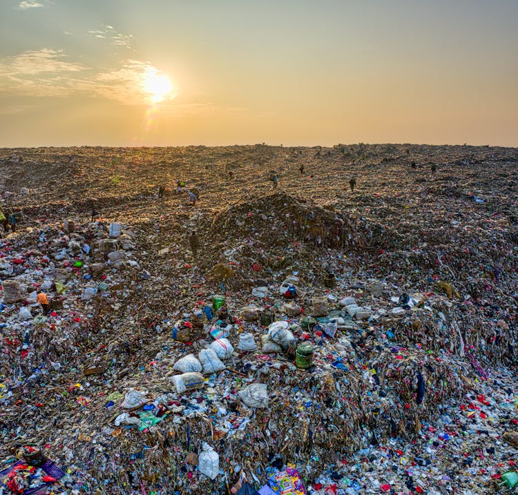 People Working On A Dump Site At Sunset