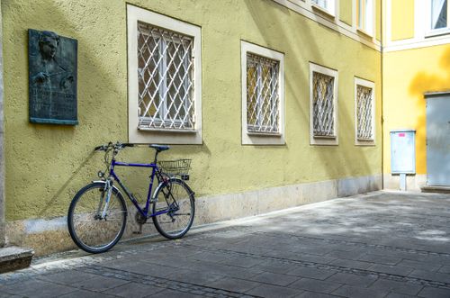 Free A vintage bicycle leans against a historical building's yellow wall in Munich's urban alley. Stock Photo