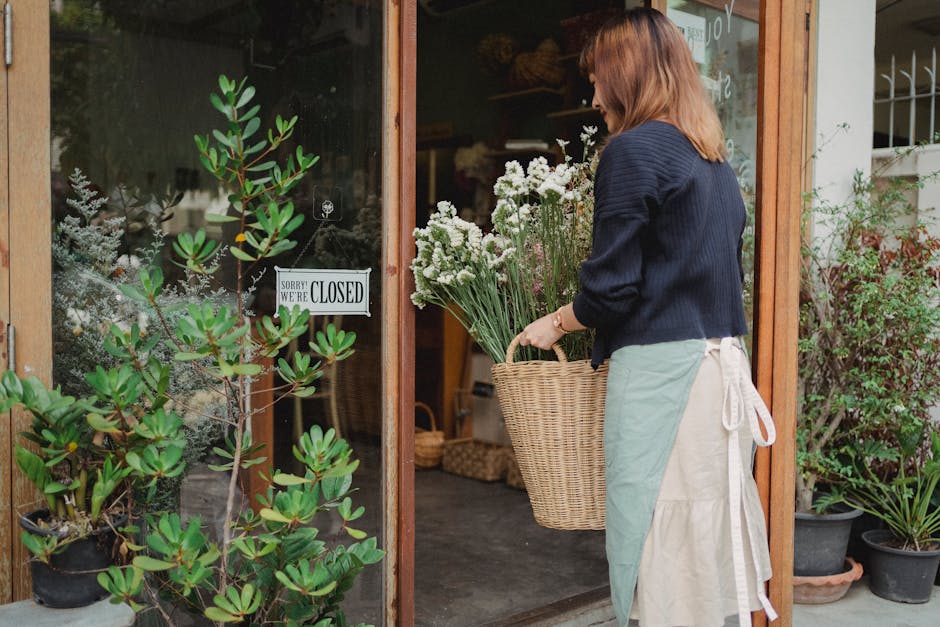 Florist arranging flowers outside a closed shop. Calm outdoor scene with florals.