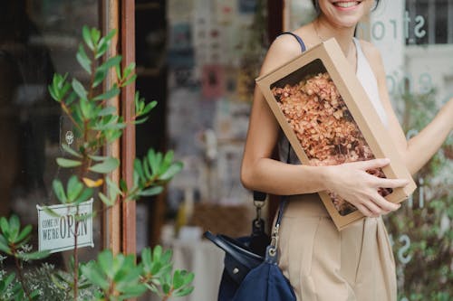 Unrecognizable woman with package standing near shop