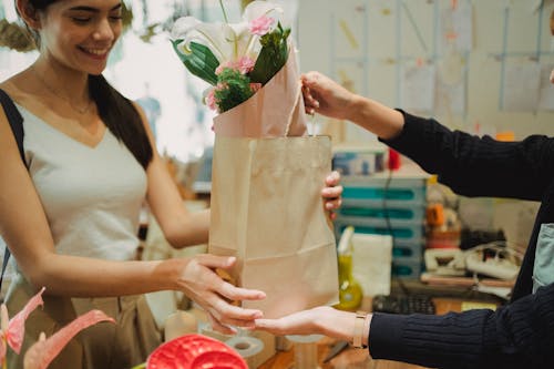 Free Flower shop assistant passing bag with bouquet Stock Photo