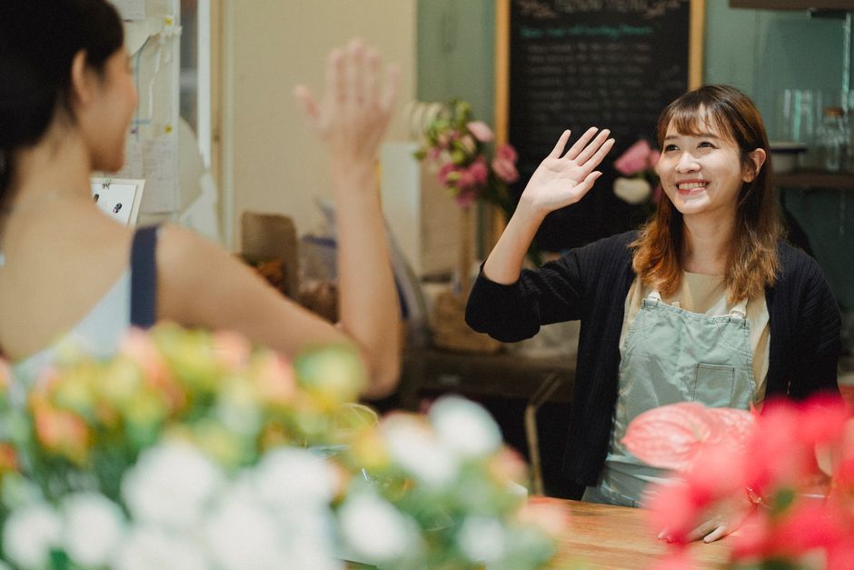 花屋でお互いを幸せそうに挨拶する二人の女性、顧客サービスを象徴しています。