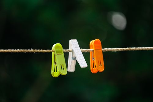 Free Close-up of green, white, and orange plastic clothespins on a clothesline with blurred background. Stock Photo