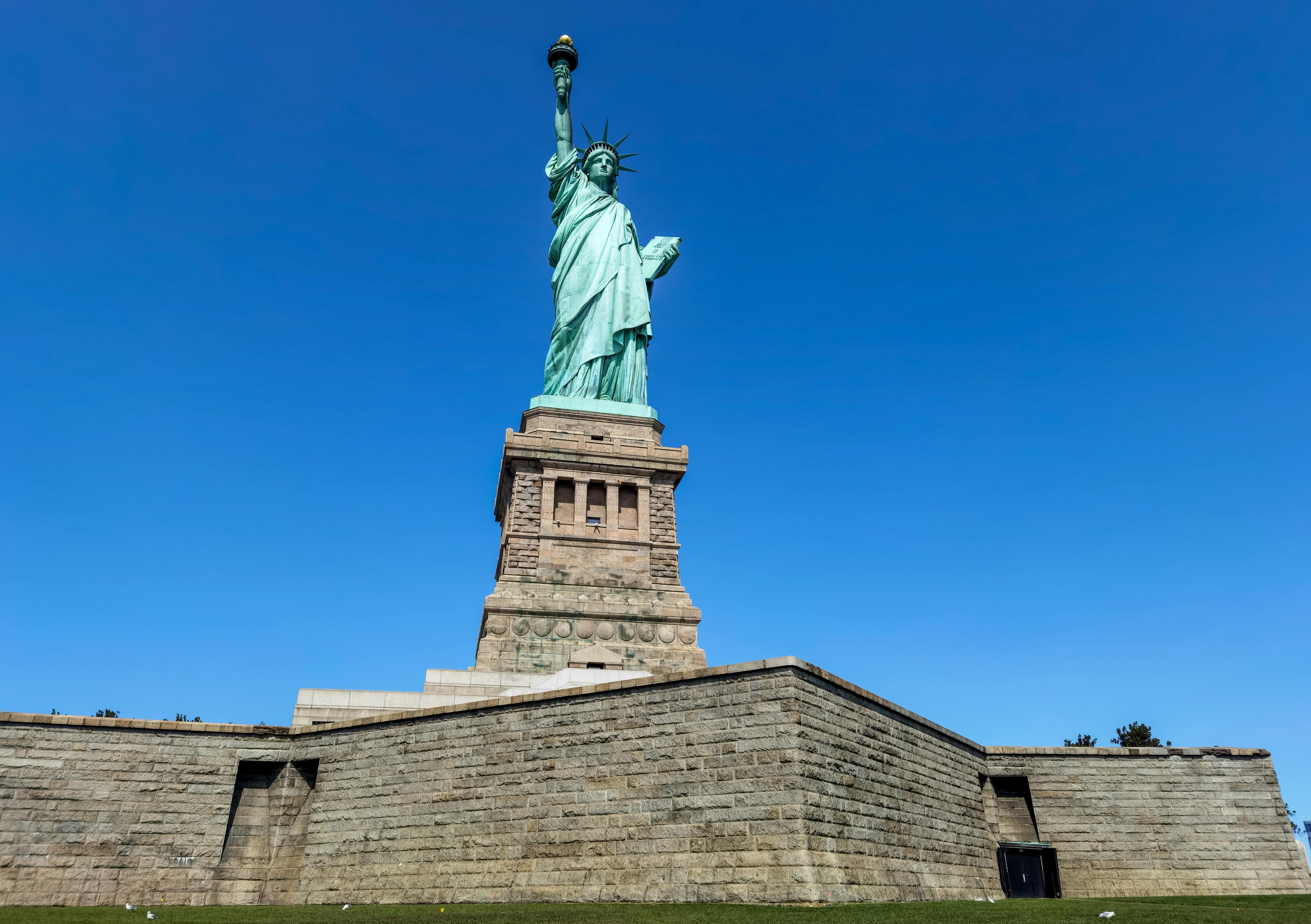 Low angle shot of the iconic Statue of Liberty under clear blue skies in New York City.