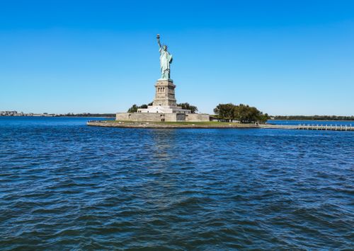 Free Iconic view of the Statue of Liberty on Liberty Island, New York, under a clear blue sky. Stock Photo