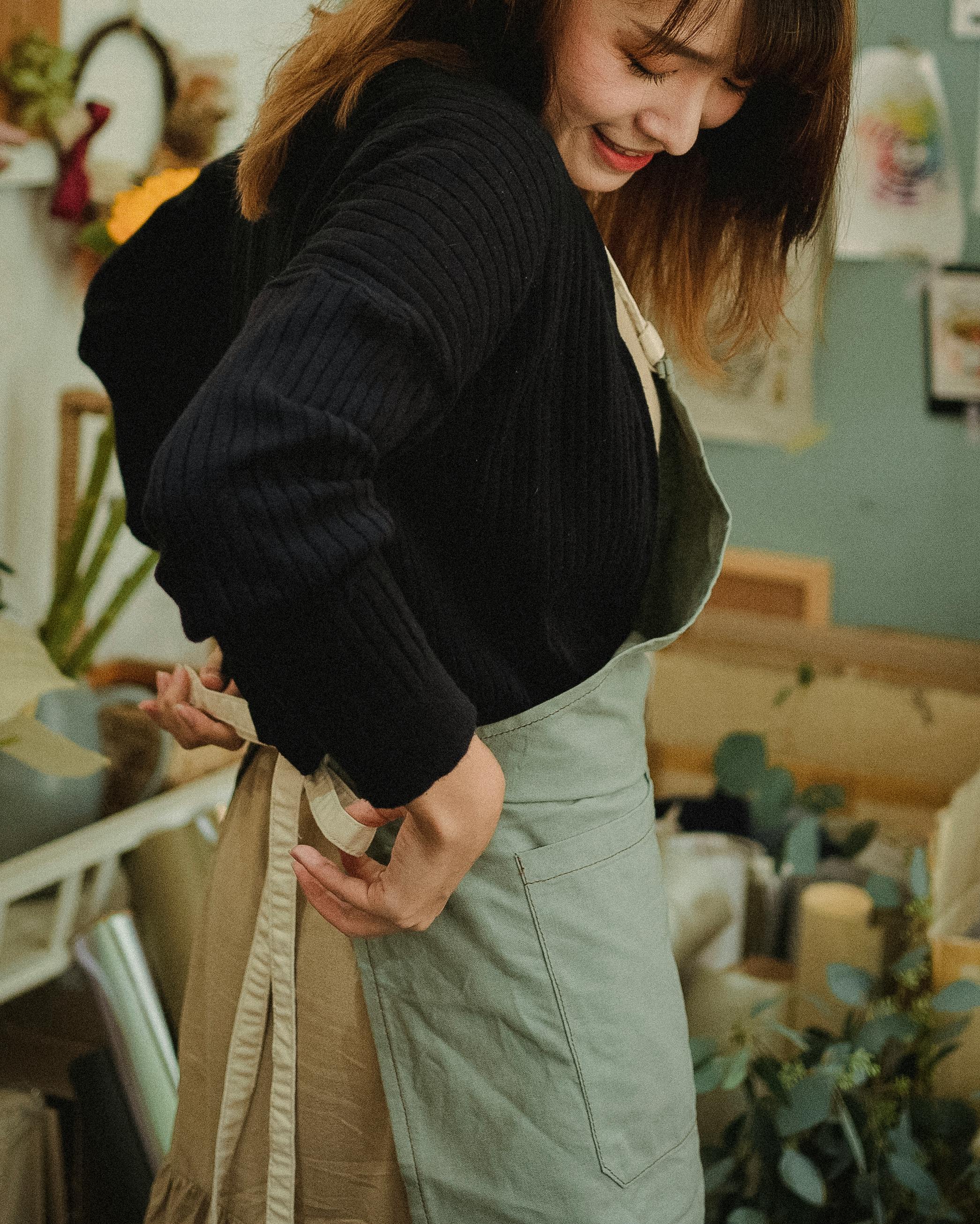 woman tying bow on apron in flower shop