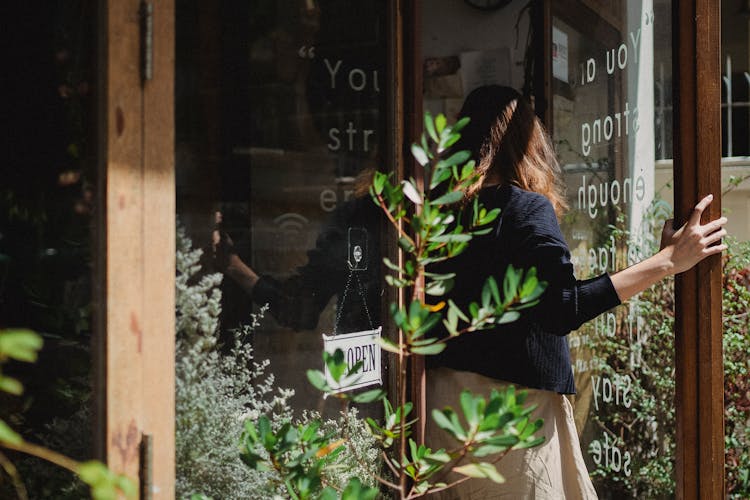 Woman Closing Door Into Flower Shop