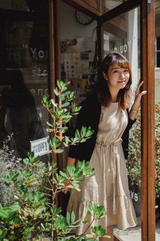 一位面带微笑的成年女性站在商店入口处，散发着温暖迷人的氛围