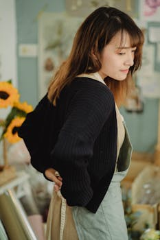 A young florist adjusts her apron as she prepares for work in a vibrant flower shop.