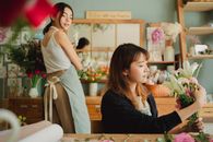 穿着休闲服、系着围裙的快乐朋友们在舒适的房间里一边参加手工作坊，一边制作鲜花