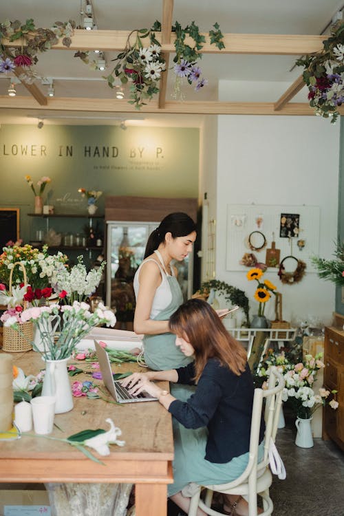 現代の花屋でラップトップに取り組んでいる焦点を絞った女性