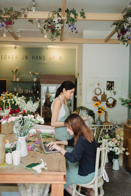 Wanita Yang Fokus Mengerjakan Laptop Di Toko Bunga Modern