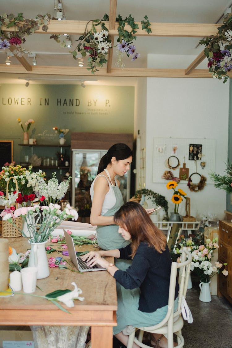 Focused Women Working On Laptop In Modern Floral Shop