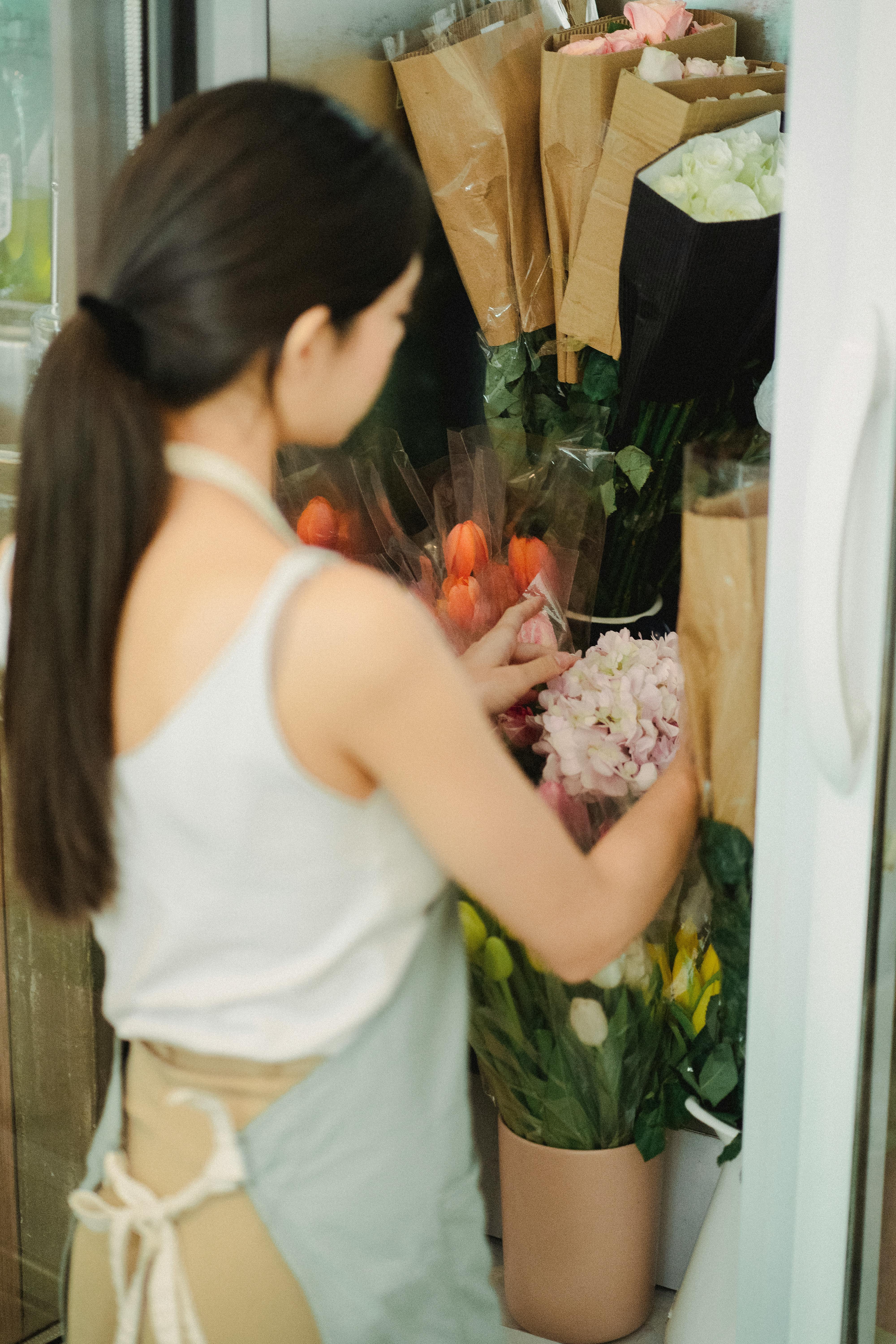 faceless woman holding flowers in fridge floral shop