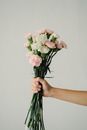Crop unrecognizable woman holding bunch of light carnations