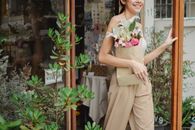 一家迷人的花店外，一位微笑的女人拿着花束