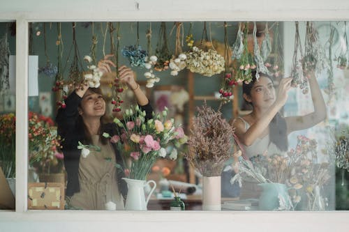 Счастливые разные флористы украшают витрину магазина цветами